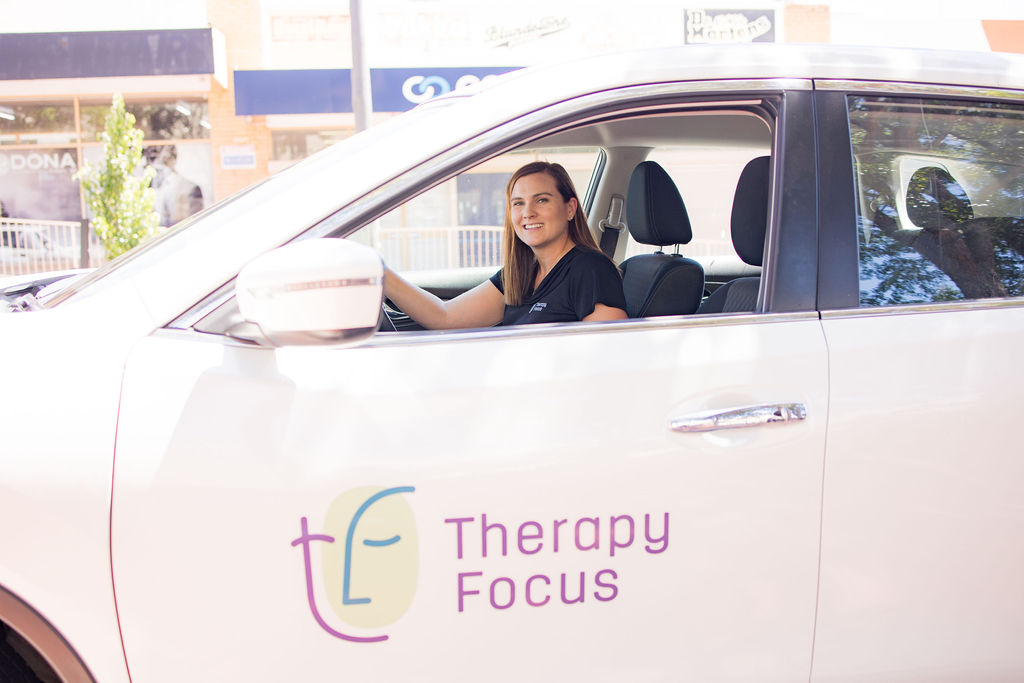 A therapist looks out the window of a Therapy Focus car. She is smiling. 