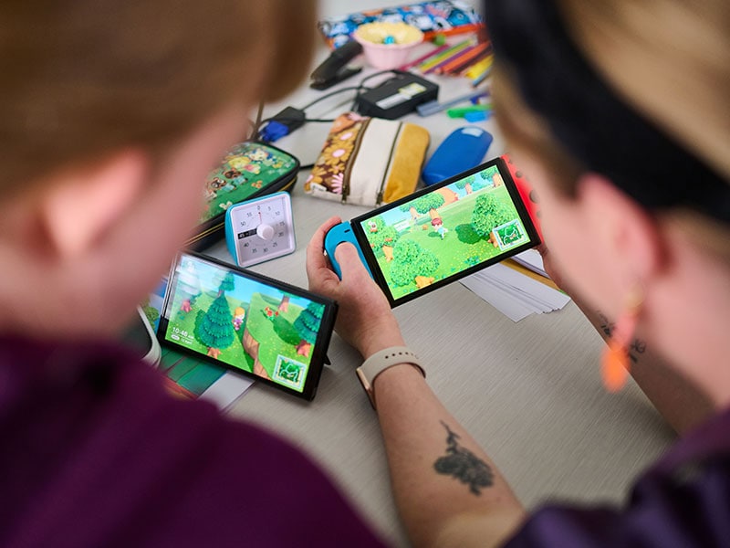 Two people looking at their gaming consoles