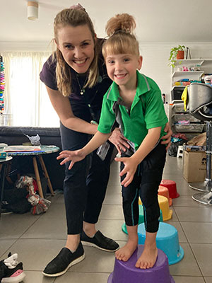 Katherine helping a young girl balance on a step