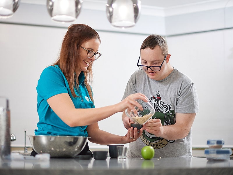 A dietitian helping a young man prepare a meal