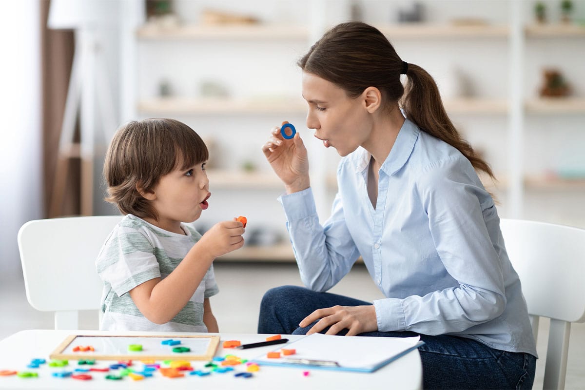 A Therapist modelling the letter O with a young boy