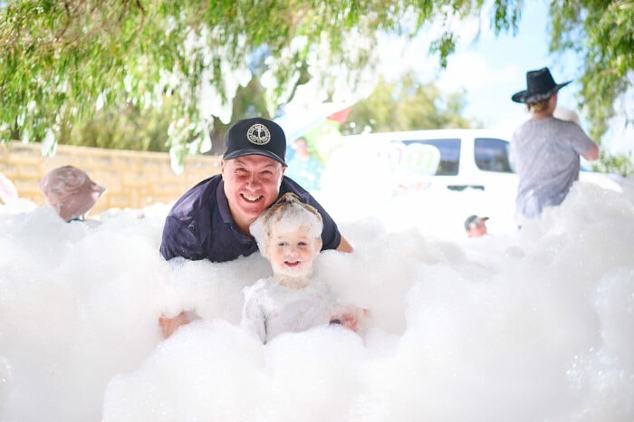 A man and toddler playing in foam