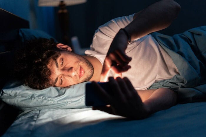 Man using smartphone in bed in a dark room